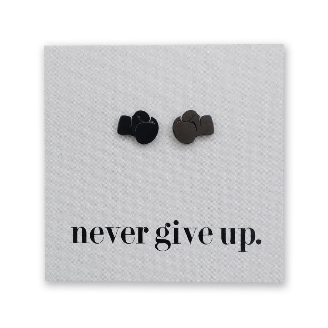 A pair of small boxing glove earrings on a light gray square backing card. , positioned above the printed black text 'never give up.