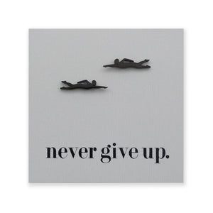 Decorative wall art with black swimming figures and 'never give up.' text on a gray background