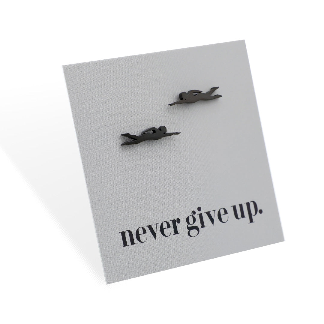 Pair of swimming-shaped earrings on a card with 'never give up.' text