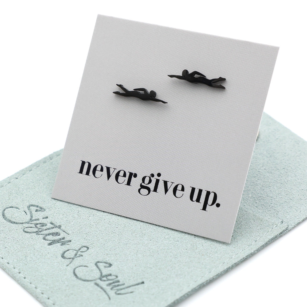 Black swimmer earrings on a card with 'never give up.' text, displayed on a light grey background gift card.