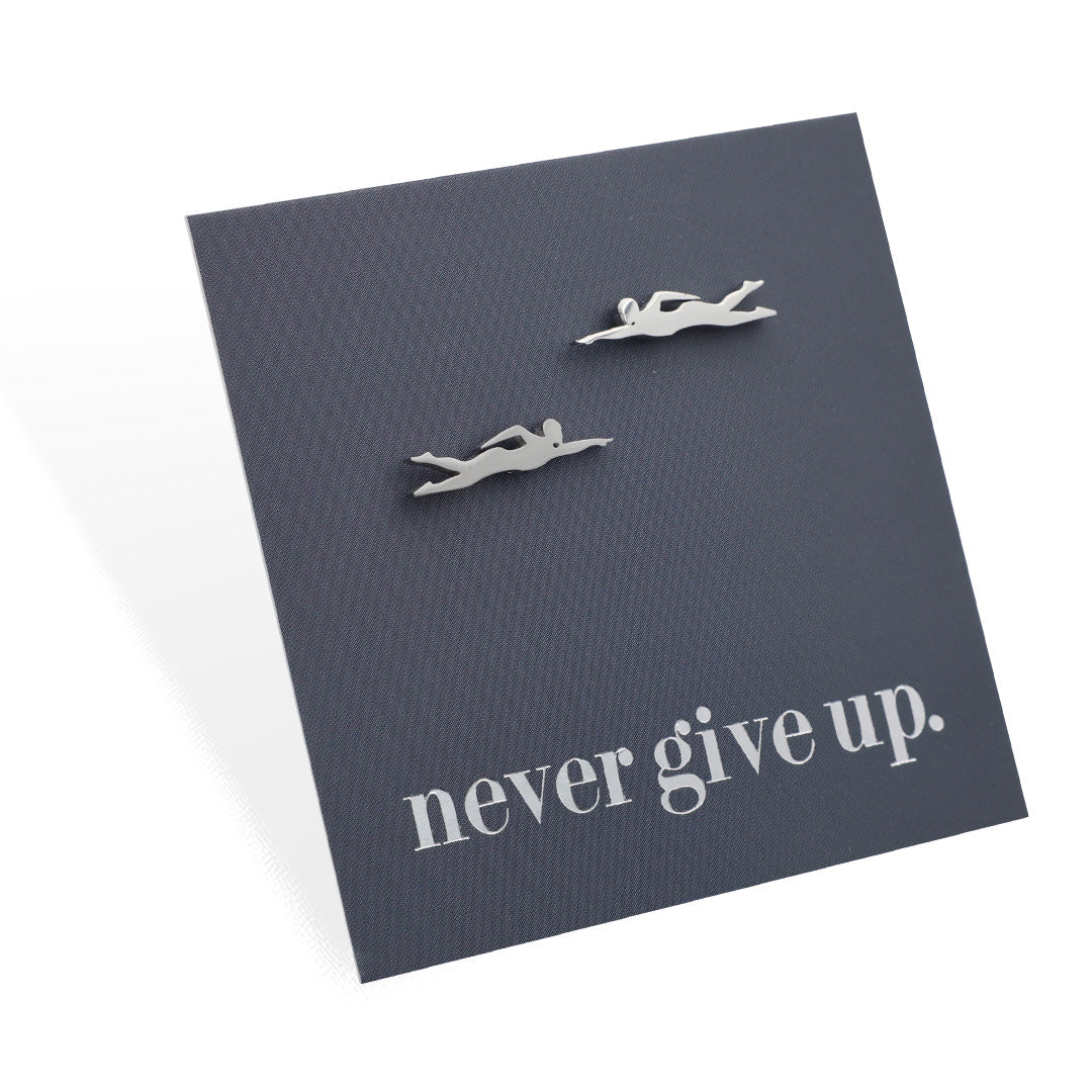 Silver swimmer earrings on a dark gray card with 'never give up.' text
