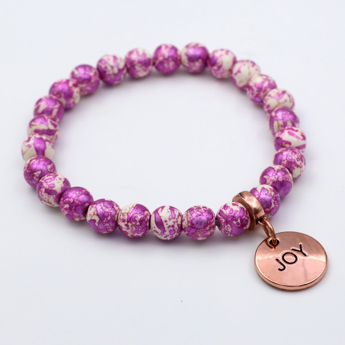 Purple and white beaded bracelet with a 'JOY' charm on a light gray background
