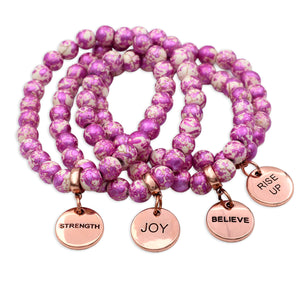 Set of pink beaded bracelets with rose gold charms on a white background