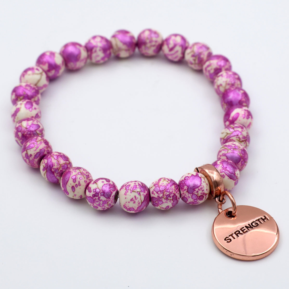Pink and white beaded bracelet with a 'STRENGTH' charm on a light gray background