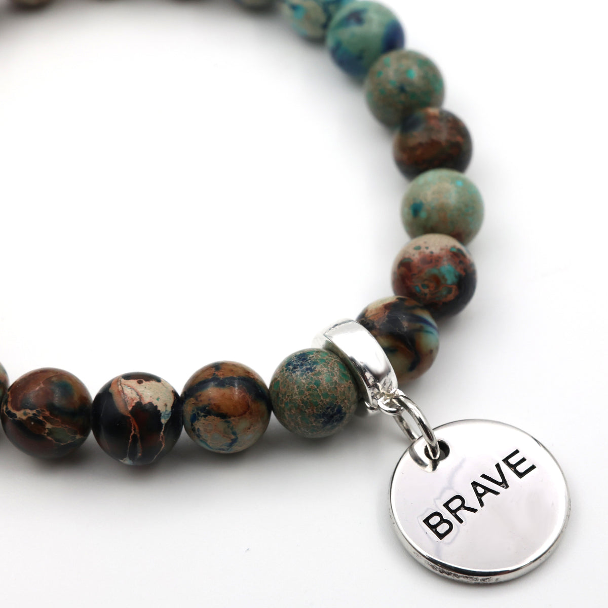 Bracelet with marbled beads and a 'BRAVE' charm on a white background
