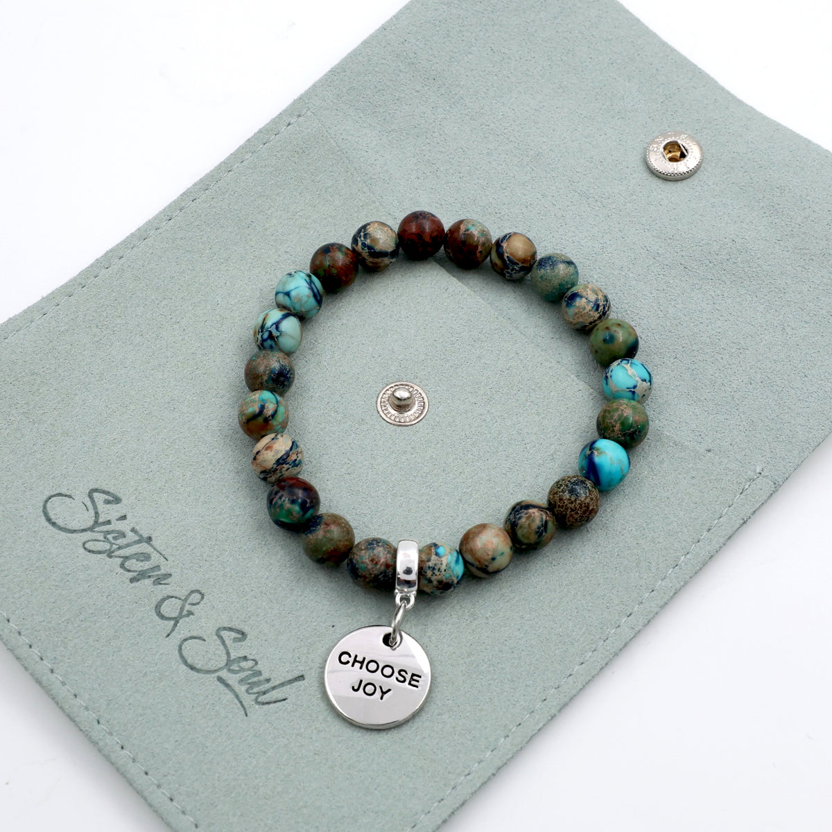 Beaded bracelet with 'Choose Joy' charm on a green card with 'Sister & Soul' branding.