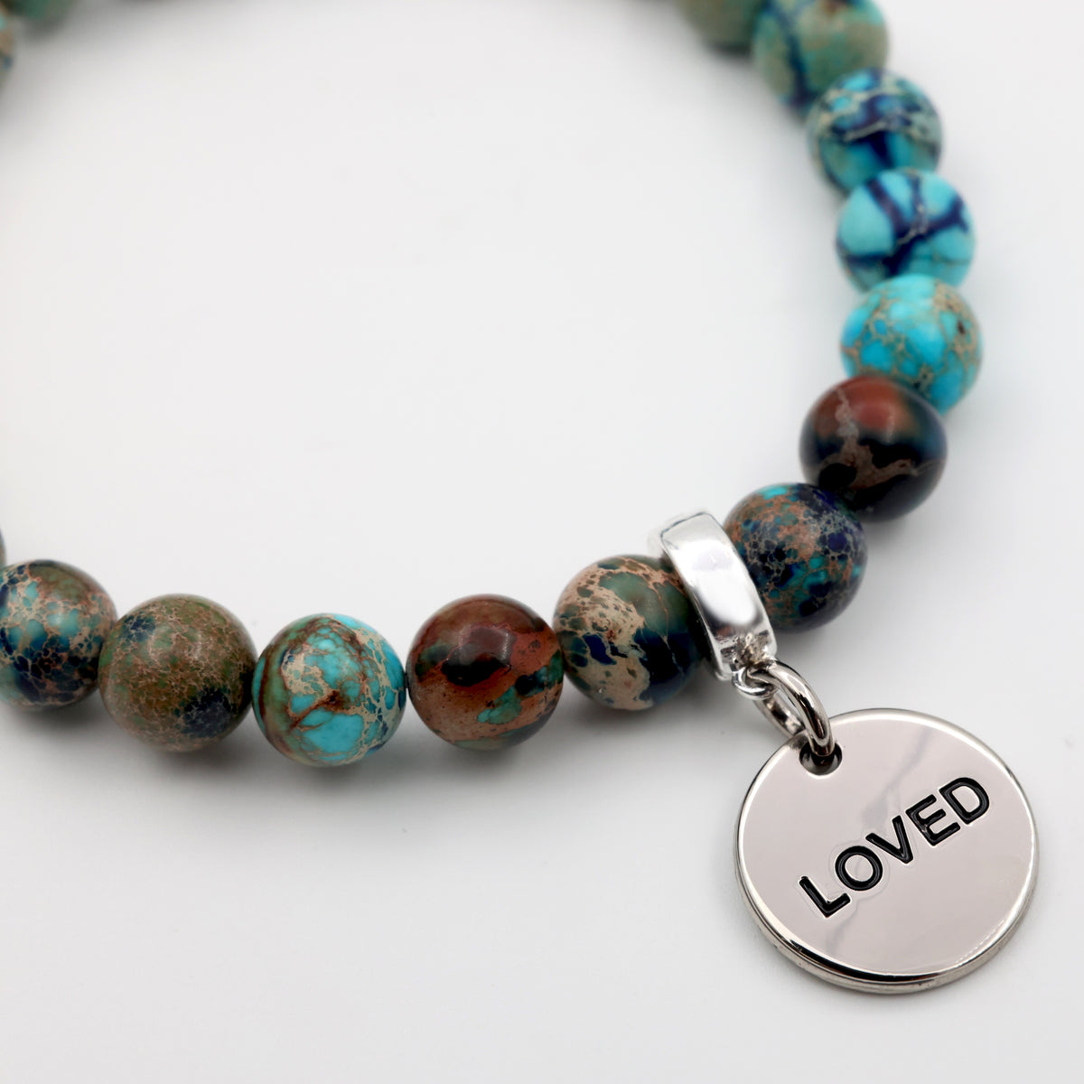 Bracelet with multicolored beads and a silver 'LOVED' charm on a white background
