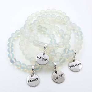 Opalite beaded bracelet with silver charms on a white background