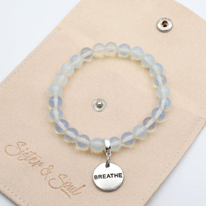 Bracelet with 'BREATHE' charm on a beige card with 'Sister & Soul' branding.