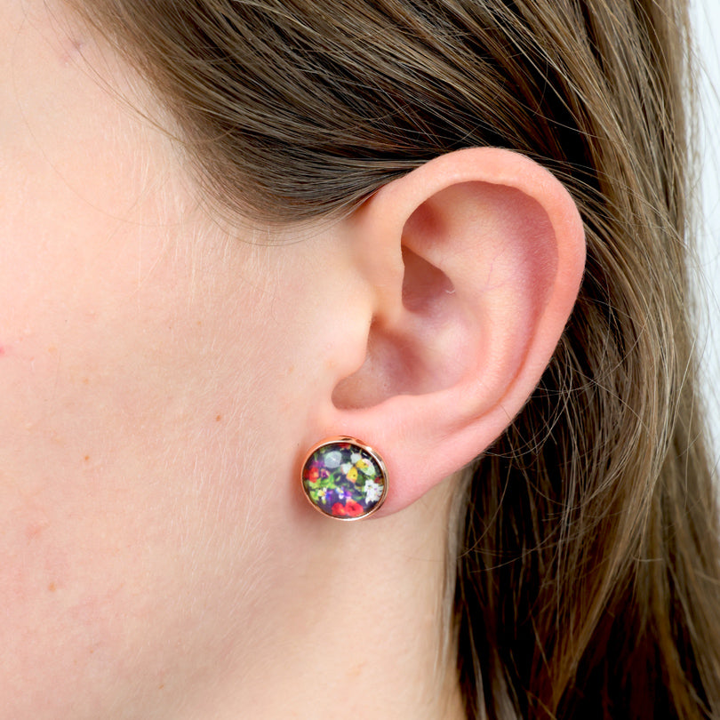 Close-up of an ear wearing a colorful stud earring with hair partially covering the frame.