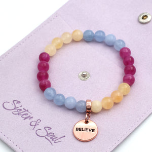 Multicolored beaded bracelet with 'BELIEVE' charm on a pink card with 'Sister & Soul' branding.