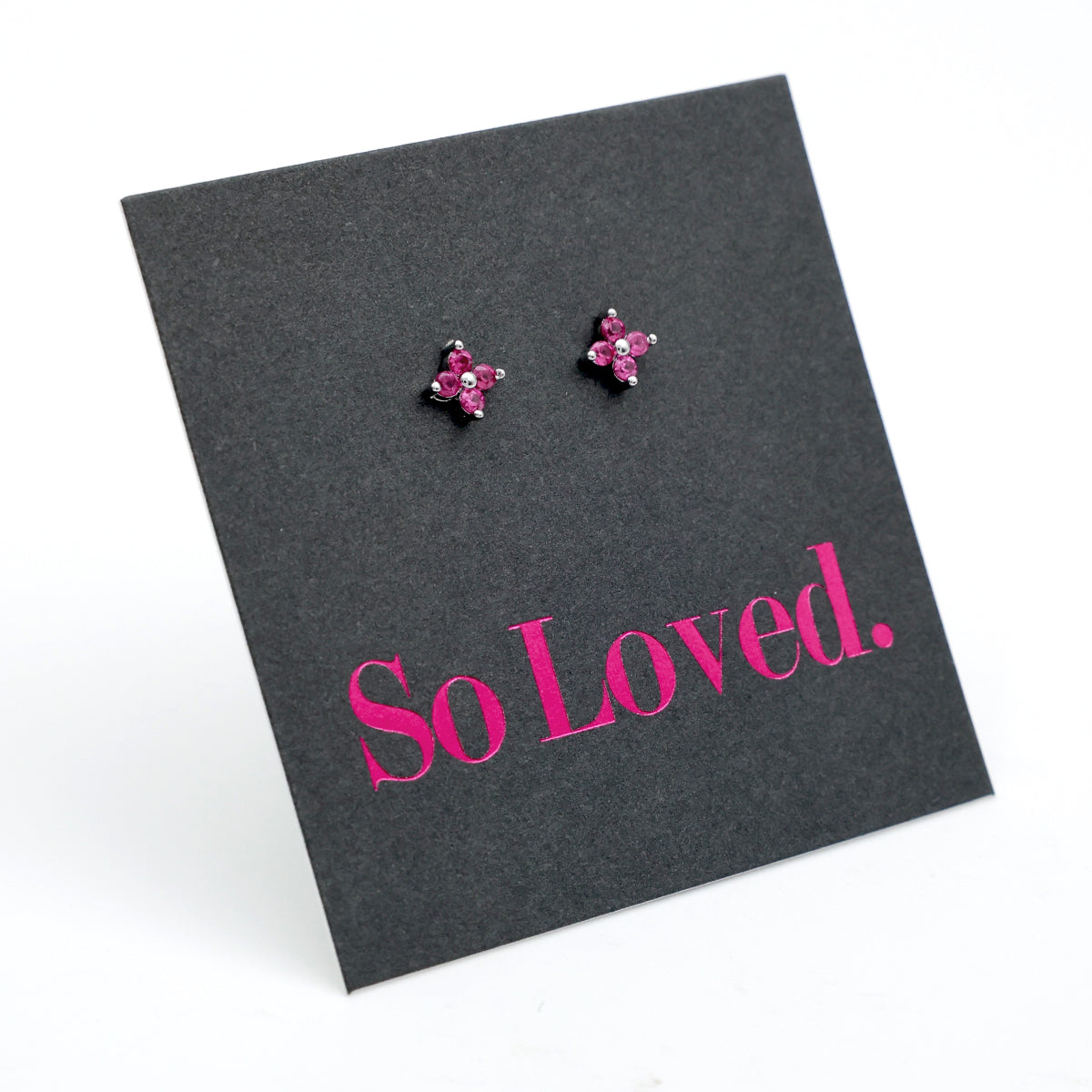 Pink tiny floral star shaped studs presented on a grey card with pink 'So Loved' writing.