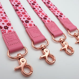 Pink floral dog leashes with rose gold hardware on a light gray background