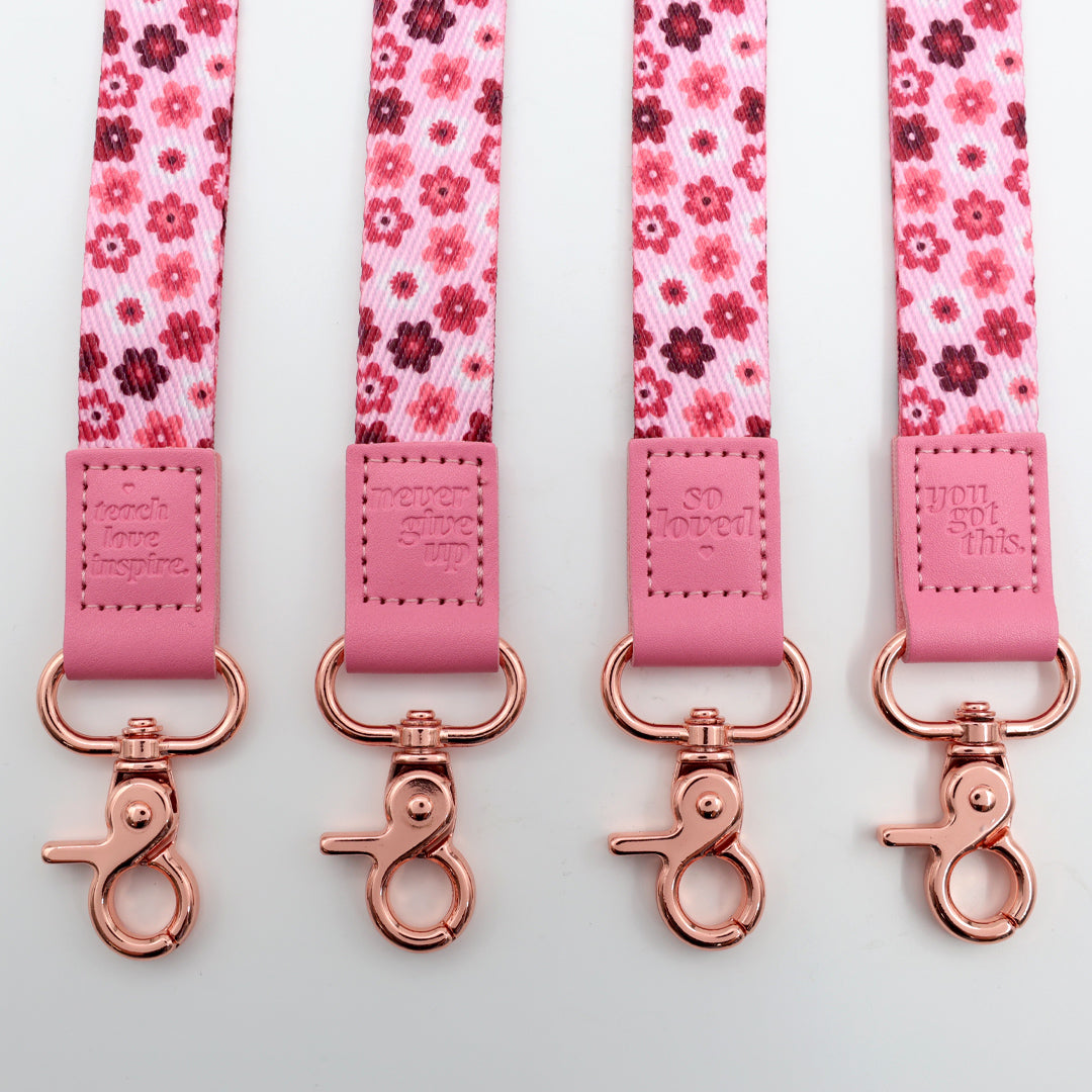 Four pink floral lanyards with rose gold clasp on a light gray background