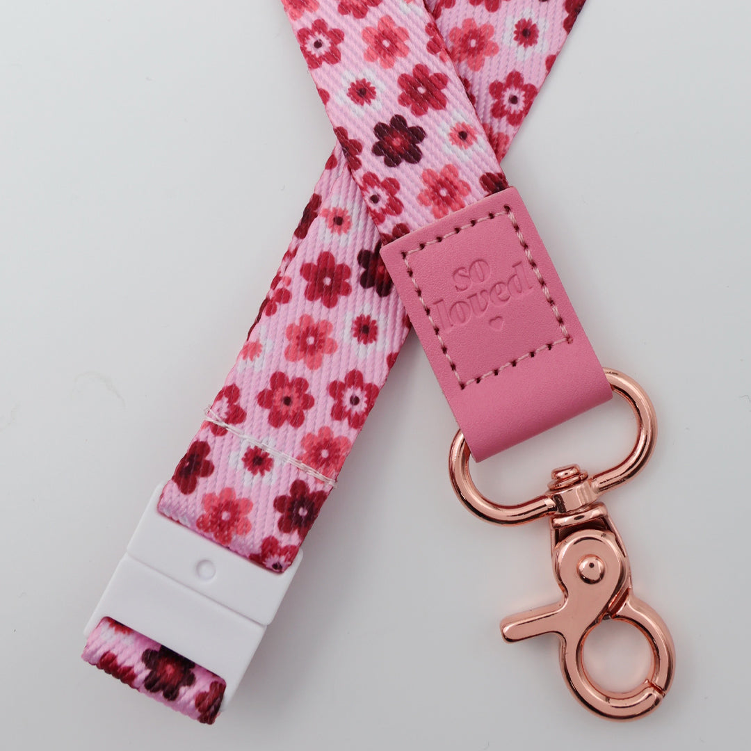 Floral patterned lanyard with pink leather tag and rose gold keychain on a light gray background