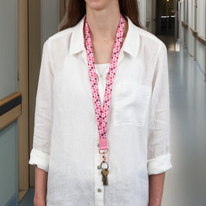 Person wearing a white shirt with a pink floral lanyard in an indoor setting