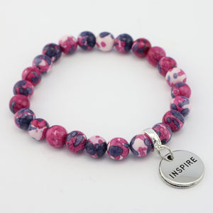 Pink and purple beaded bracelet with a silver 'INSPIRE' charm on a white background