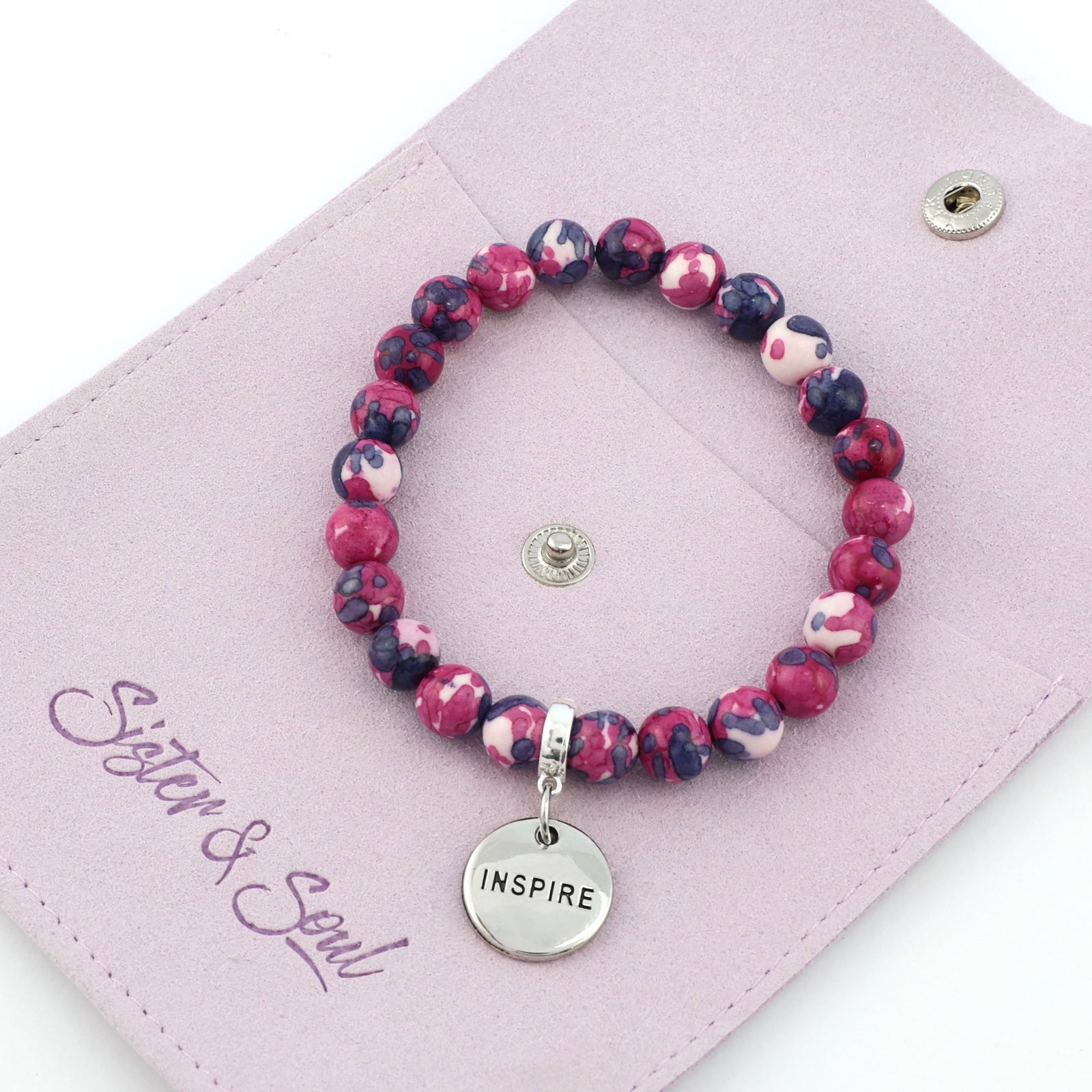 Set of pink and purple beaded bracelets with inspirational charms on a white background