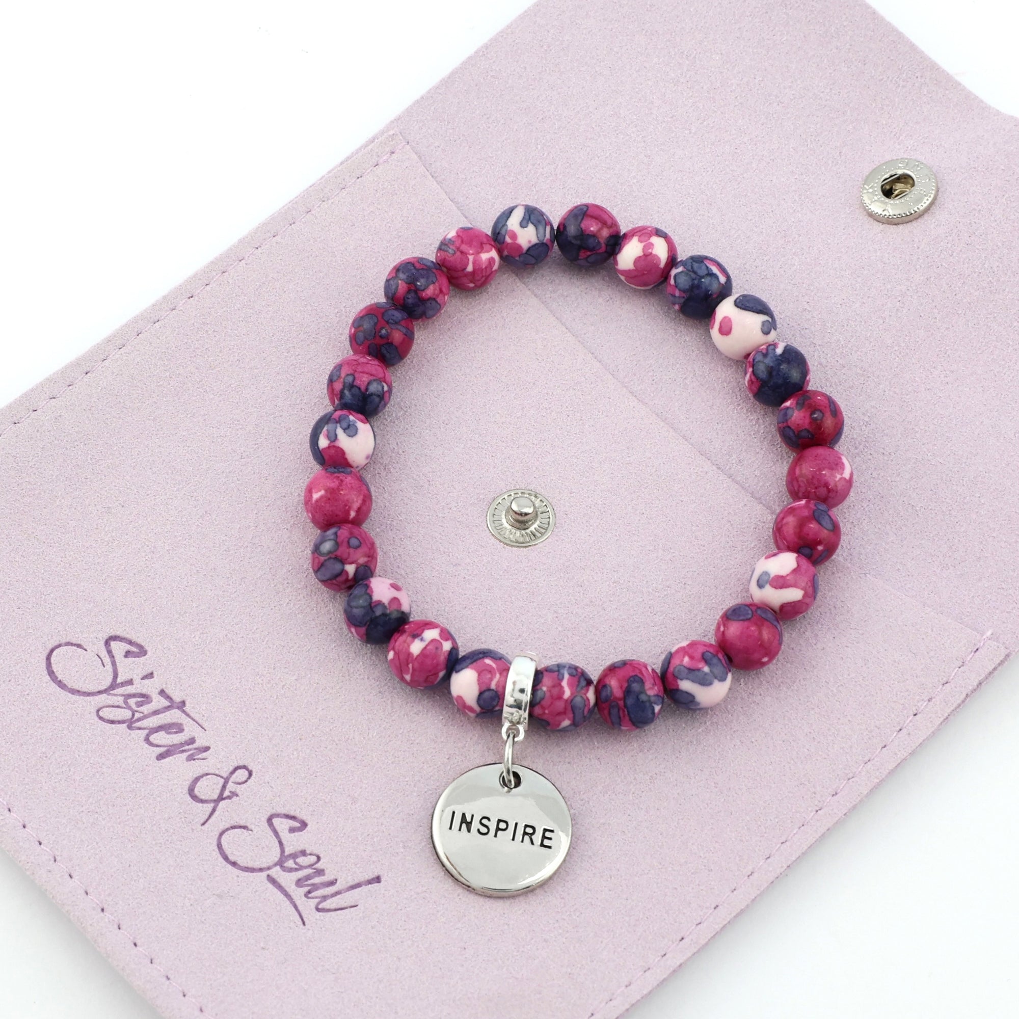 Set of pink and purple beaded bracelets with inspirational charms on a white background