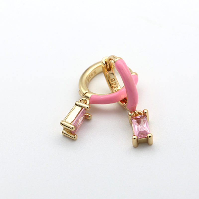 Gold and pink earring on a white background
