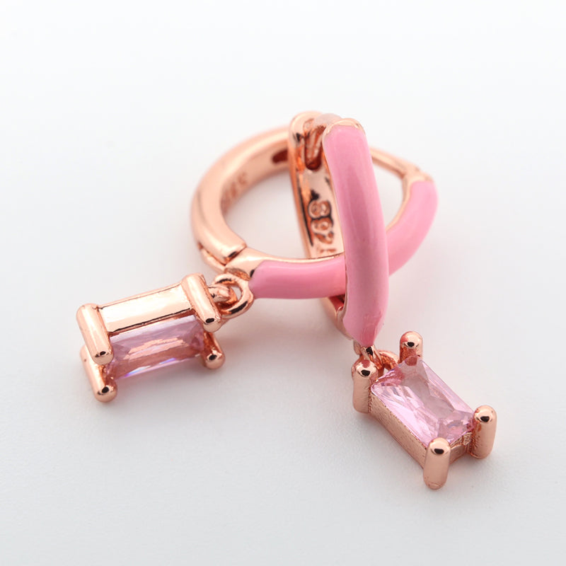 Rose gold and pink earring with gemstones on a light gray background