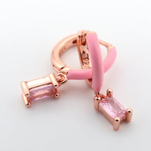 Rose gold and pink earring with gemstones on a light gray background