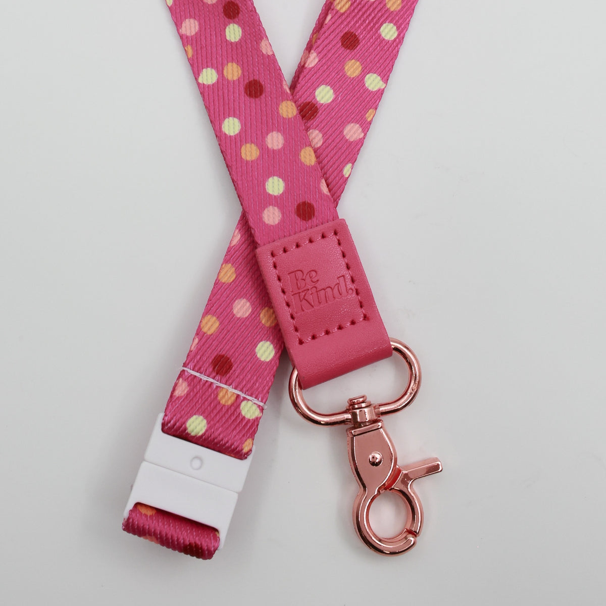 Be Kind embossed on a pink polka dot lanyard with pink trim and a lobster clasp.