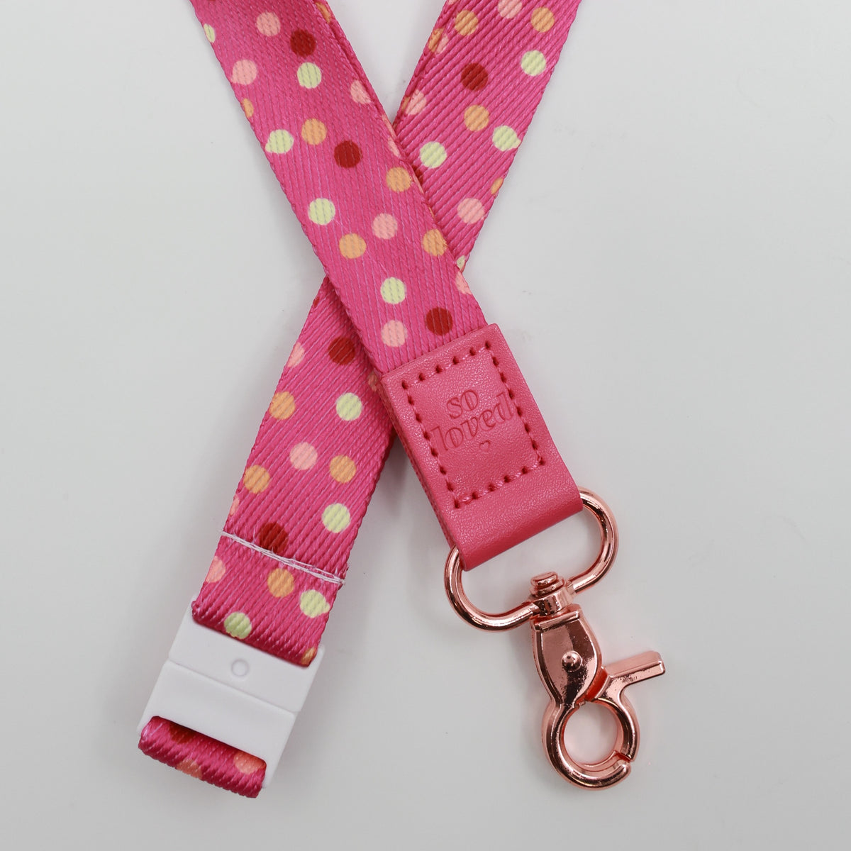 So Loved embossed on a pink polka dot lanyard with pink trim and a lobster clasp.