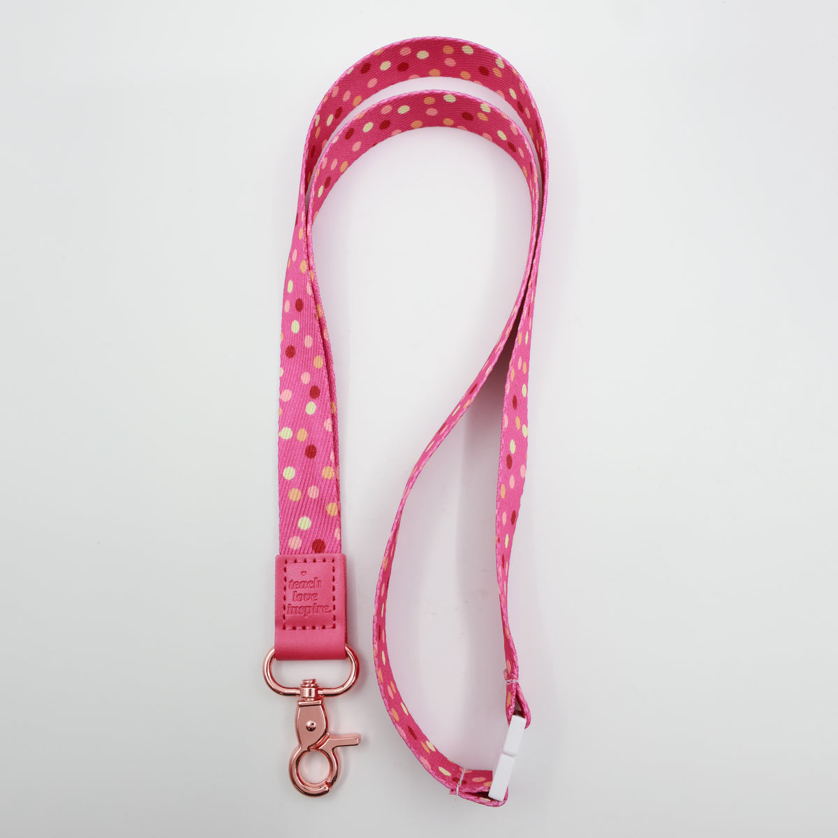 Teach Love Inspire embossed on a pink polka dot lanyard with pink trim and a lobster clasp.
