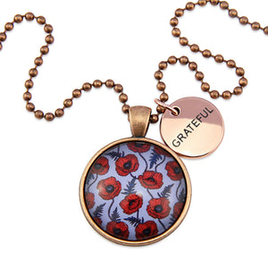 Necklace with floral pendant and 'GRATEFUL' tag on a white background