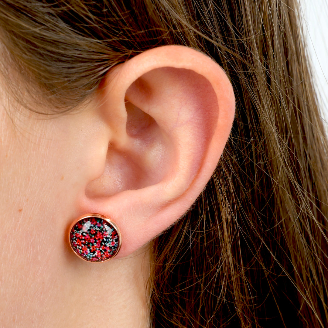 Close-up of an ear wearing a round earring with a colorful design.