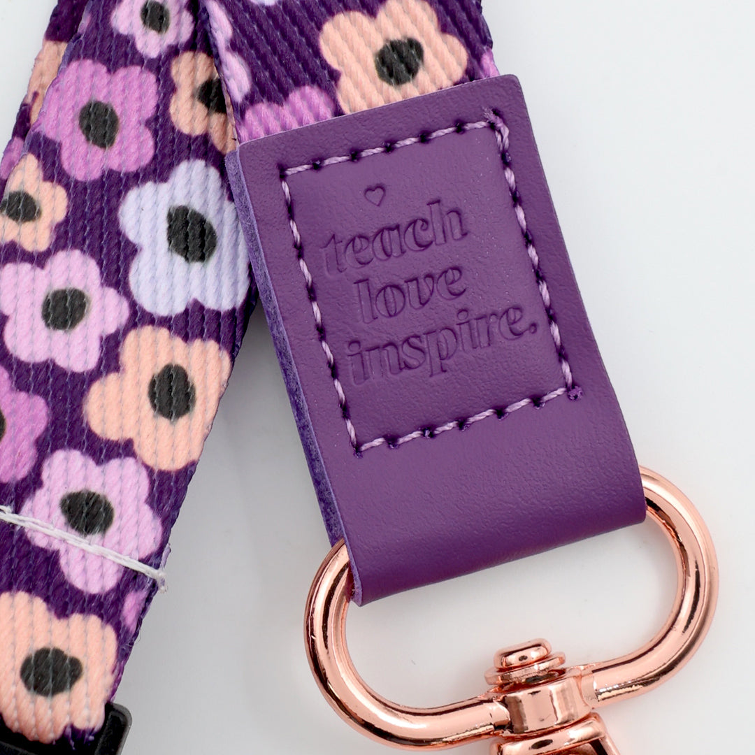 Purple strap with floral pattern and 'teach love inspire' text, featuring a rose gold keychain.
