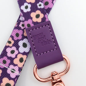 Floral-patterned strap with a purple tag and rose gold keychain on a white background