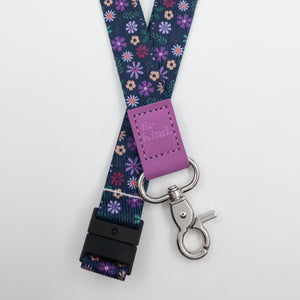 Be Kind embossed on a navy floral lanyard with purple trim and a lobster clasp.