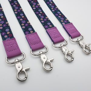 Purple Floral lanyards showing Be Kind, Teach Love Inspire, You Got This and So Loved embossed trims and lobster clasps.