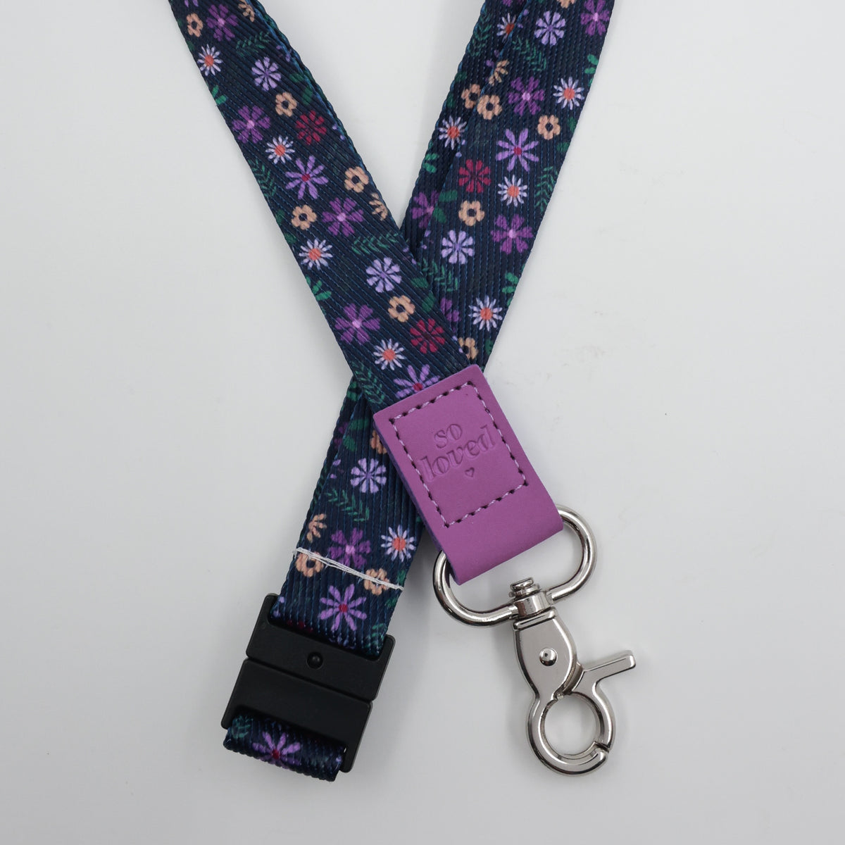 So Loved embossed on a navy floral lanyard with purple trim and a lobster clasp.