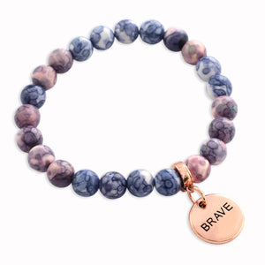 Purple marbled beaded bracelet with a 'BRAVE' charm on a white background