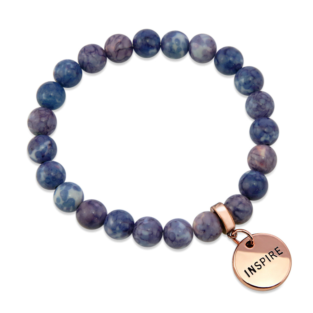 Two bracelets with purple and storm patch agate stone beads and rose gold word charms, one with 'INSPIRE' and the other with 'WARRIOR'.
