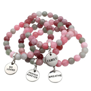 Pink and gray beaded bracelets with engraved charms on a white background