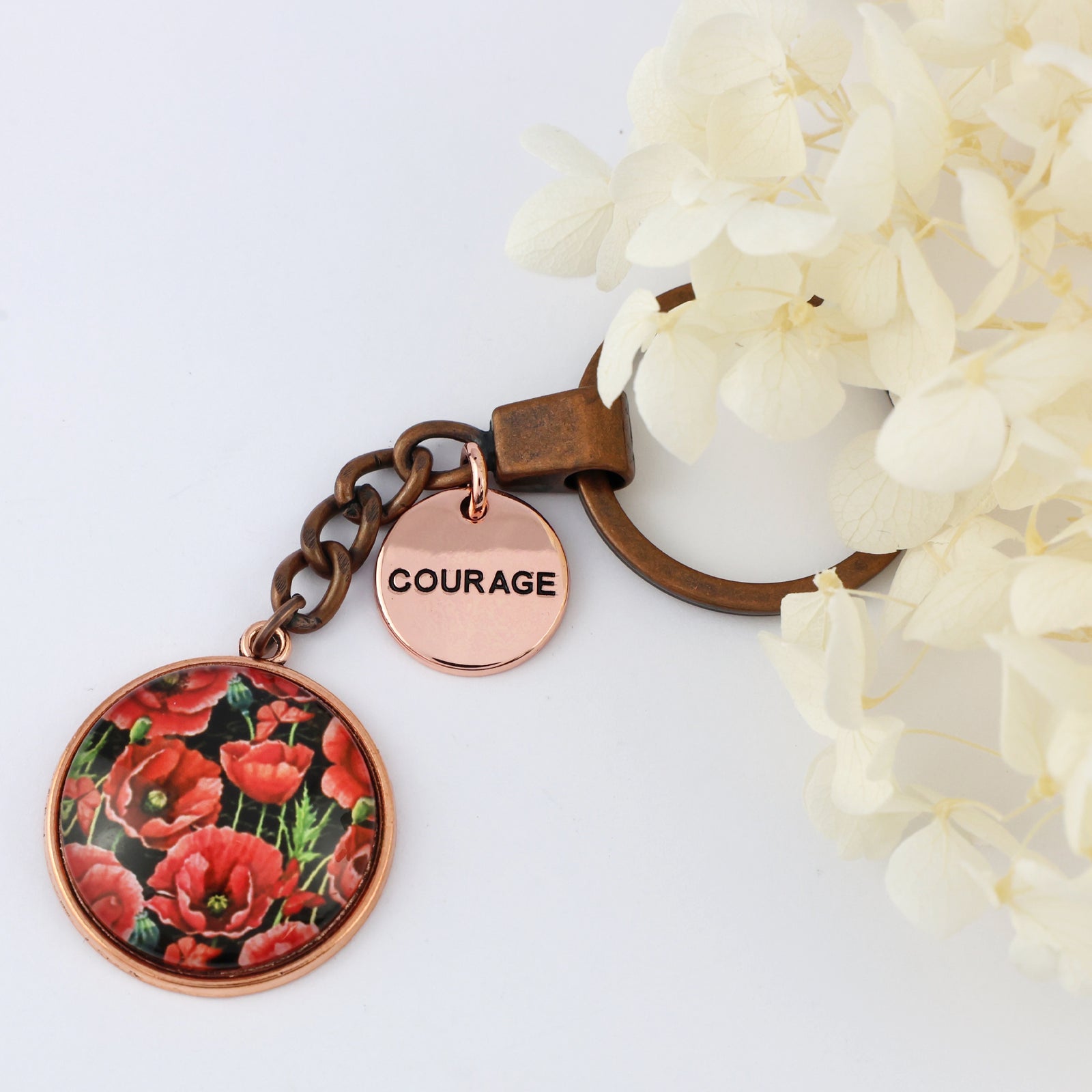 Keychain with floral design and 'COURAGE' charm on a white background