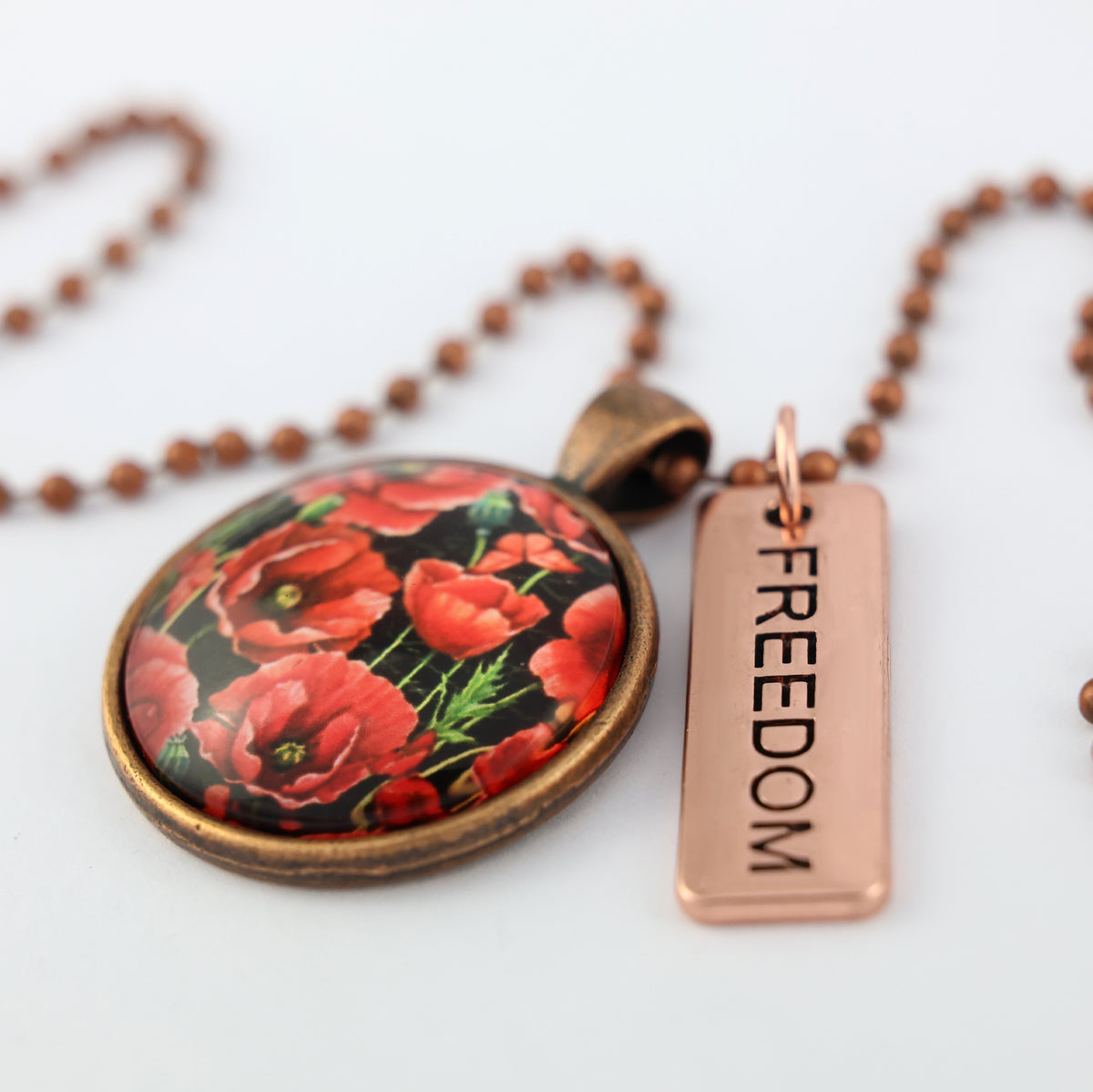 Necklace with floral pendant and 'FREEDOM' tag on a white background