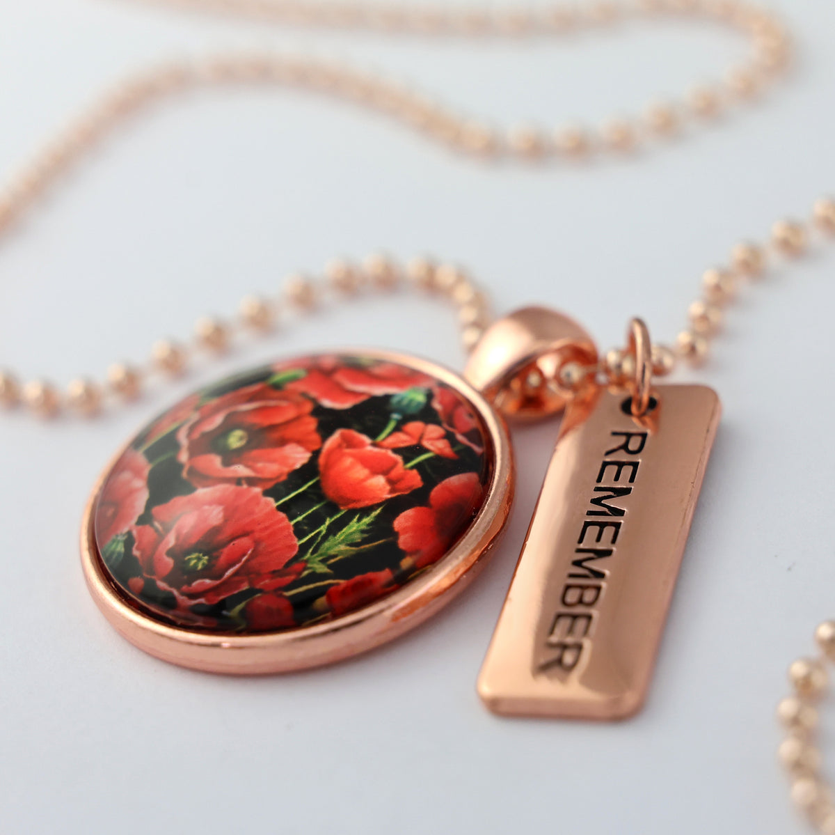Necklace with floral pendant and 'REMEMBER' tag on a light background