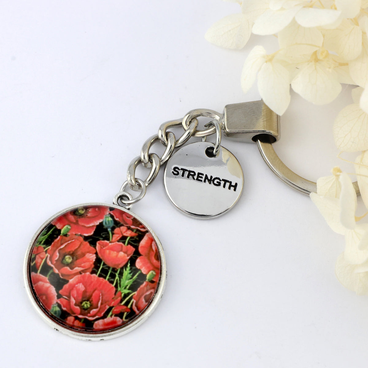 Keychain with floral design and 'STRENGTH' tag on a white background