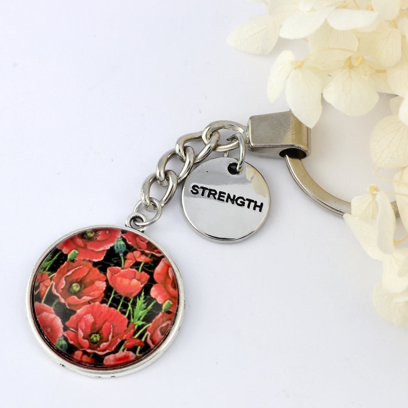 Keychain with floral design and 'Strength' tag on a white background