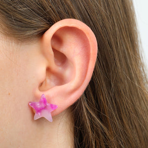 Close-up of an ear wearing a pink star-shaped earring.