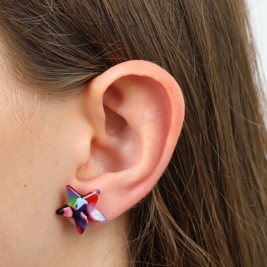 Close-up of an ear wearing a colorful butterfly earring with hair partially obscuring the view.