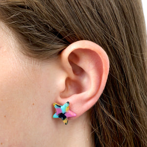 Close-up of an ear wearing a colorful star-shaped earring 