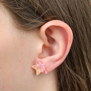 Star-shaped earring worn on a person's ear with brown hair.