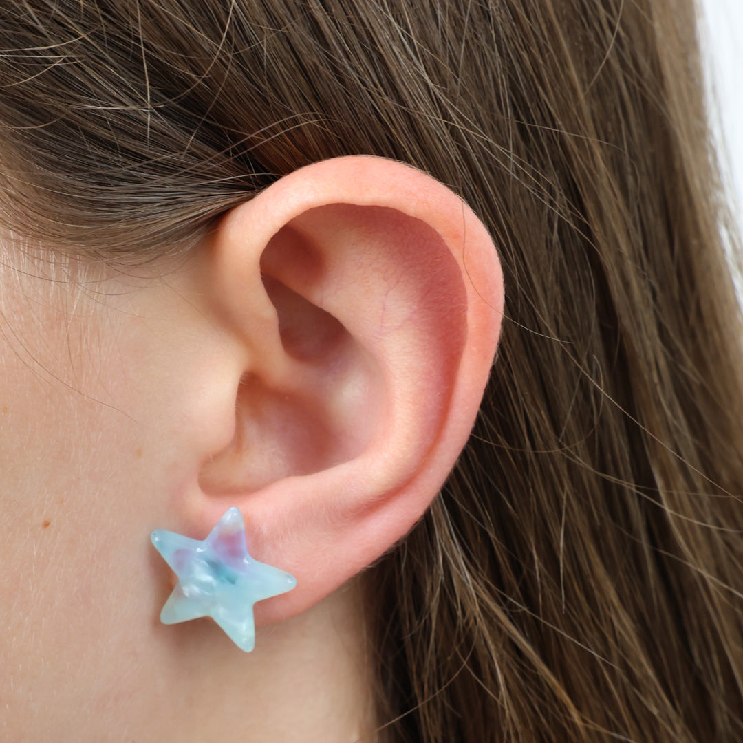 Star-shaped earring worn on a person's ear with brown hair.