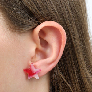 Close-up of an ear wearing a red and pink star-shaped earring.